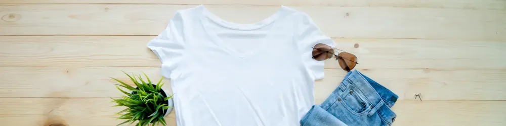 Flaty lay of white t-shirt, a plant, jeans, and sunglasses